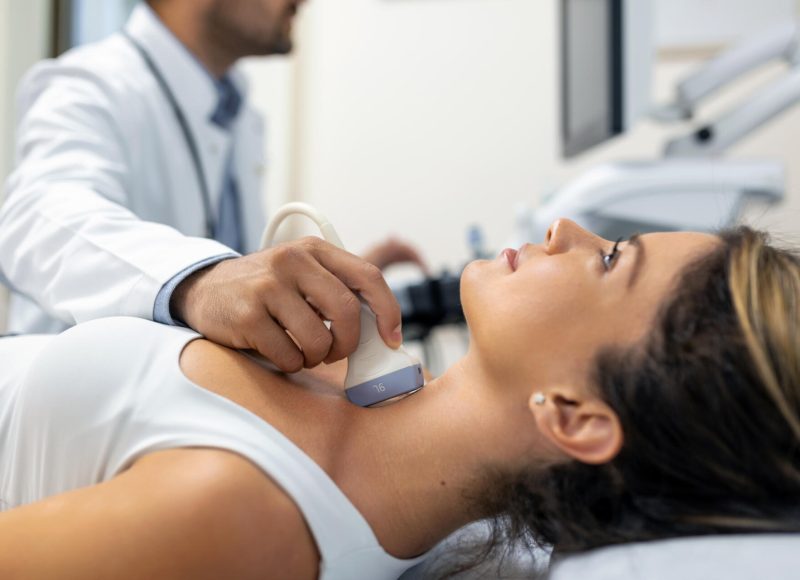 Close up shot of young woman getting her neck examined by doctor using ultrasound scanner at modern clinic
